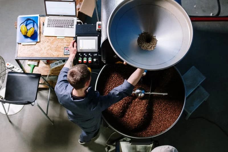 A worker operating equipment in a small-batch coffee roastery