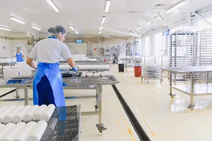 A worker in protective gear handling product in a processing facility
