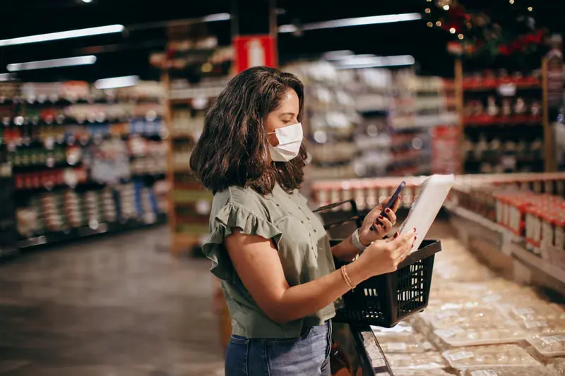Shopper checking a product label on her phone in a grocery aisle